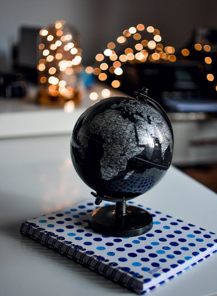 Services-02 Elegant black globe and notebook against warm bokeh lights, perfect for educational themes.
