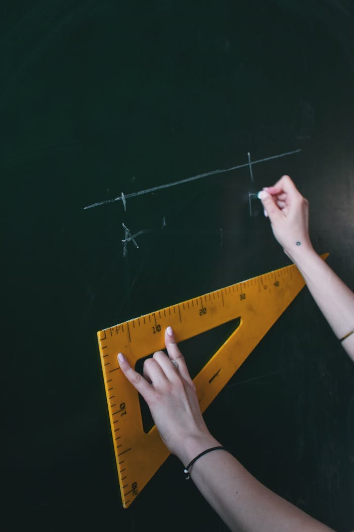 creative-03 Two hands drawing a line with chalk on a blackboard using a triangle ruler